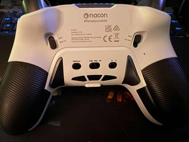 the back of a white controller with black buttons and grips