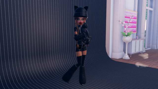 Wearing all black and holding a black cat in Roblox Dress To Impress.