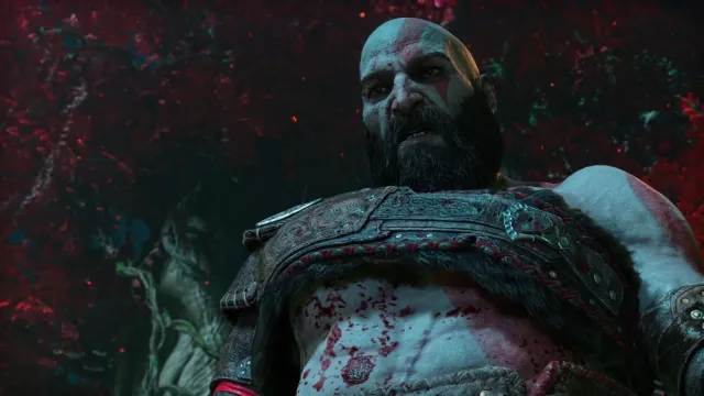 A bearded and bloody old warrior glares down something off screen. Image of Kratos from God of War Ragnarok