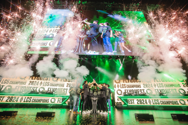 FlyQuest raise the trophy as fireworks explode above the LCS Summer Championship stage.