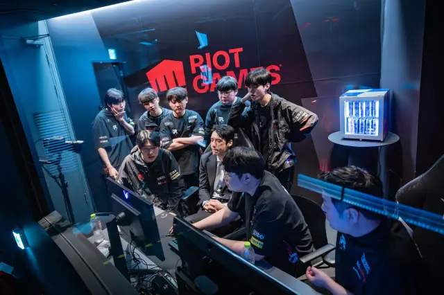 KT Rolster players and coaches gather around a computer at the Riot Games LCK Arena to discuss their League of Legends plans