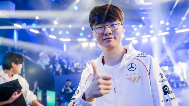 Faker gives a thumbs up to the camera with crowds of people and lights flashing behind him