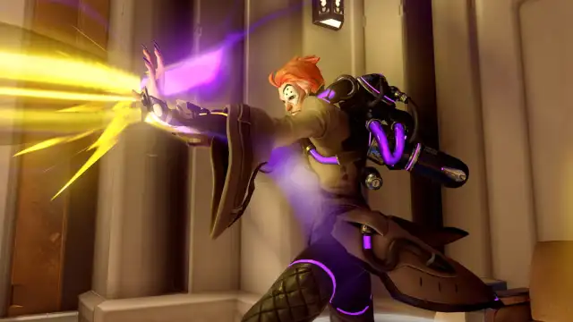 Moira shoots a yellow beam of light from her hand while purple light shines from her clothing.