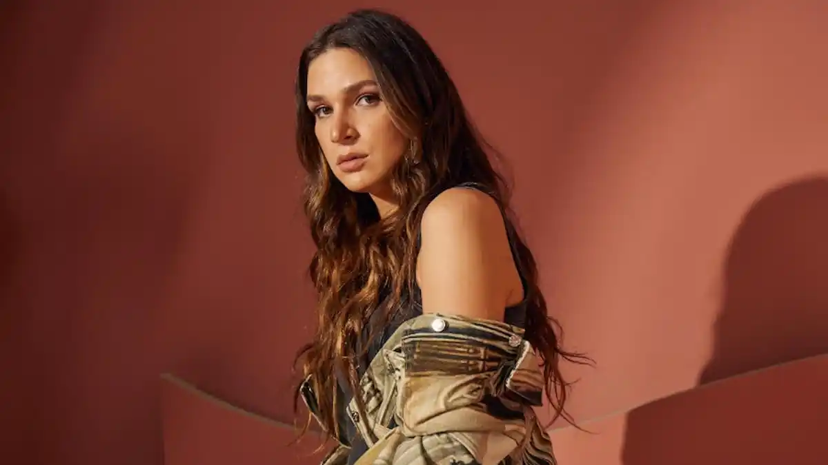 A white woman with long brown hair on a burgundy background.