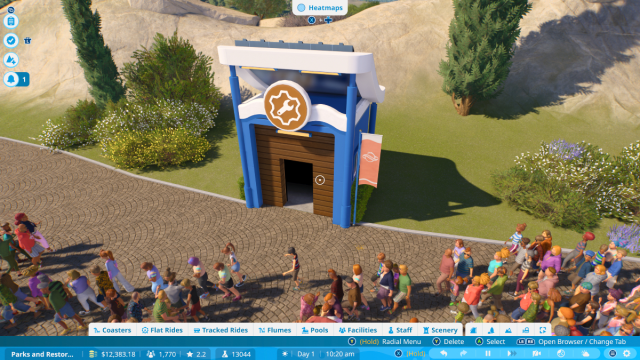 A workshop in Planet Coaster 2 beside a path packed with guests.