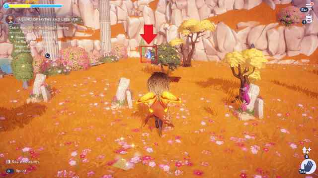 The player chasing a blue Will-o’-the-Wisp creature in the flowery fields of Mythopia in Disney Dreamlight Valley.