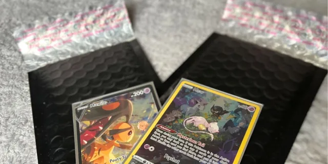 Mawile and Mew Pokemon cards on top of black bubble mailers.