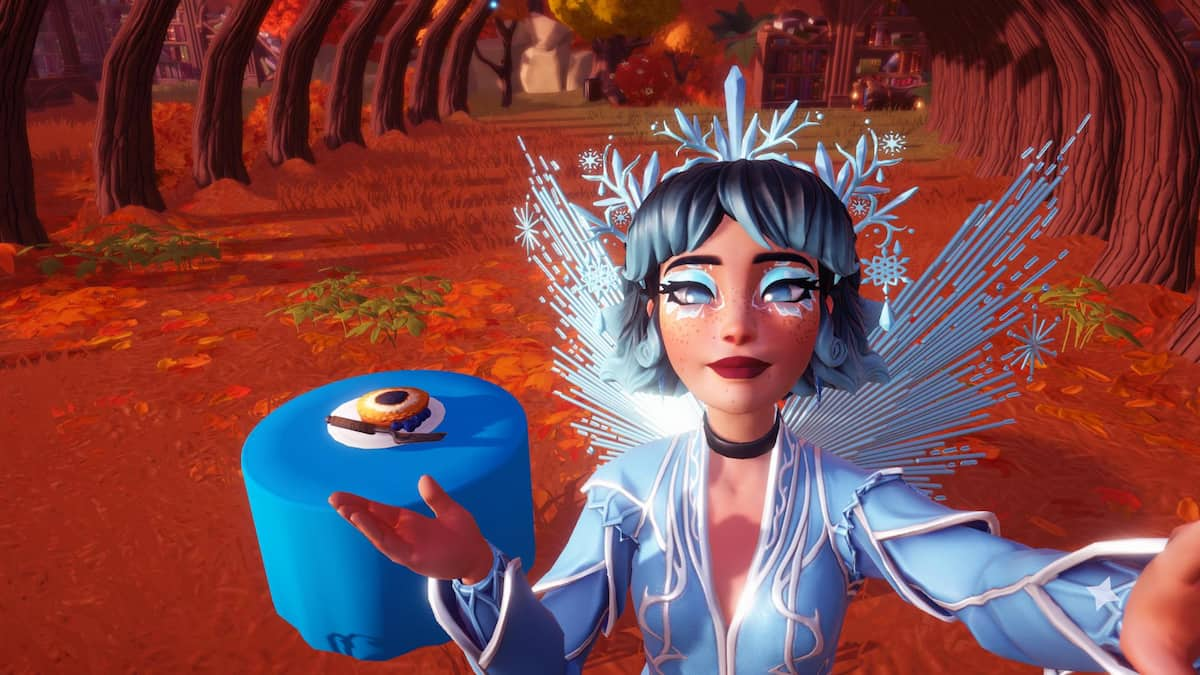 A player wearing an icy blue tiara, wings, and dress holding out their hand to highlight a blueberry pie sitting on a table with a bright blue tablecloth in Disney Dreamlight Valley.