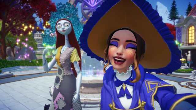 A player wearing a big witch hat smiling with their eyes closed while taking a picture with Sally in Disney Dreamlight Valley.