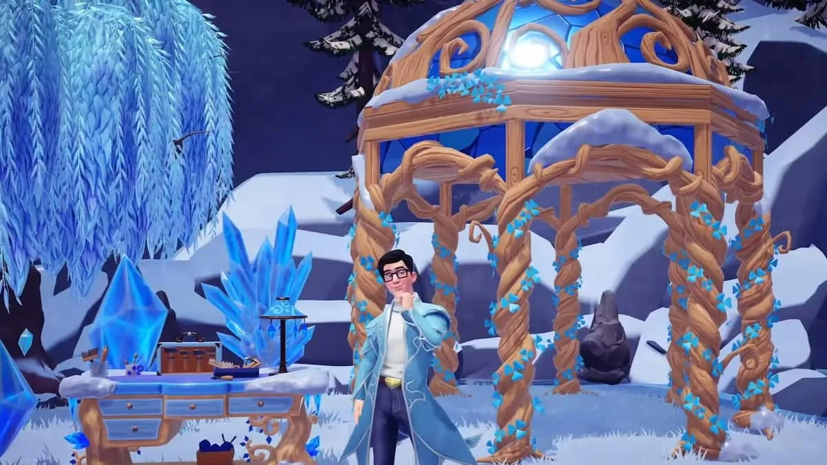 A player wearing black glasses and a long blue coat holding their chin while thinking and standing by an icy crafting table and a light brown gazebo in Disney Dreamlight Valley.