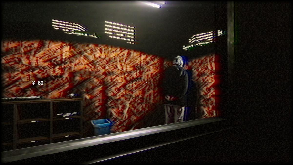 A man standing in the corner of a booth, looking at the wall