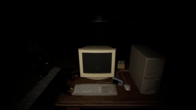 A dark shot of an old school pc in the protagonist's home in Cursed Digicam