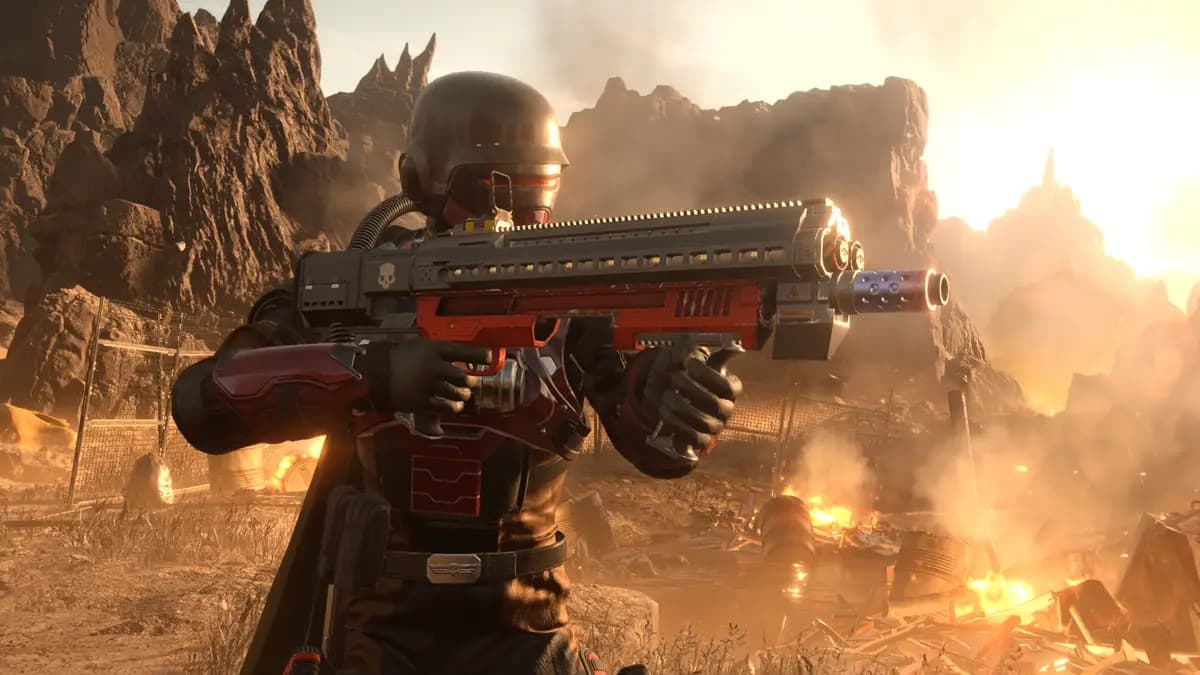 An image from Helldivers 2 of a soldier standing on a battlefield with a large assault rifle. This soldier is wearing red and black armor.