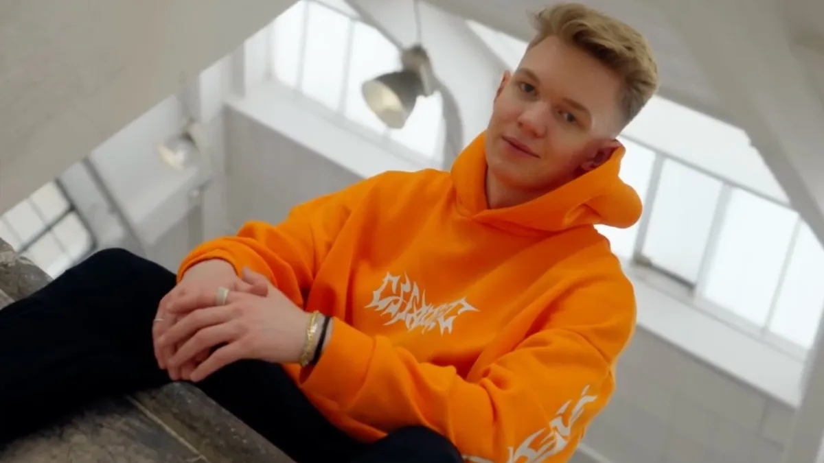 setty in an orange hoody sitting in a white room