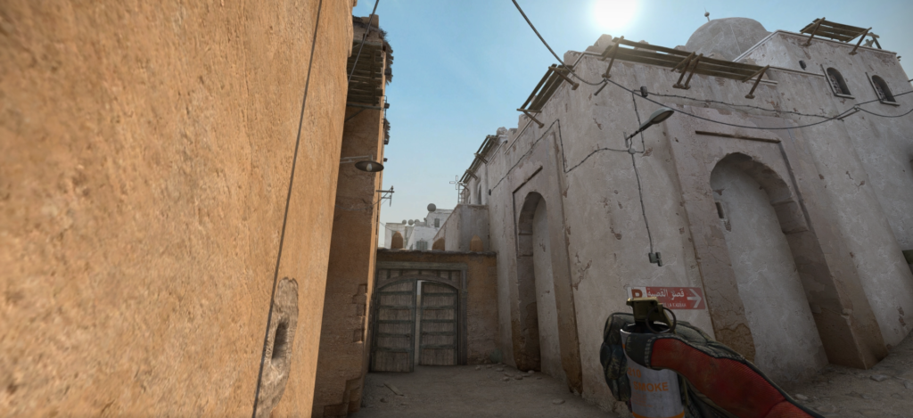 A CS:GO player standing at bottom mid-CT spawn on Dust 2, holding a smoke and preparing to throw.